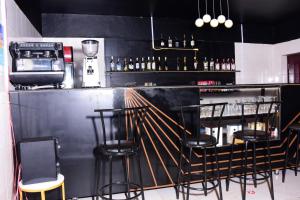 een bar met zwarte stoelen en een bar met flessen bij Le Ptit Zinc in Kigali
