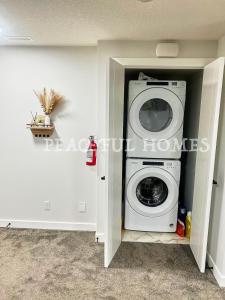 a laundry room with a washer and dryer at Peaceful Homes - Elegant 2 Bedroom Suite in Calgary