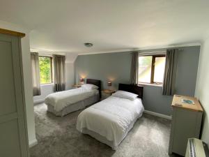 ein Schlafzimmer mit zwei Betten und zwei Fenstern in der Unterkunft Rosecraddoc Manor - Riverbank in Saint Cleer