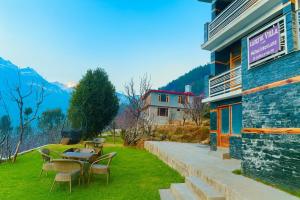 eine Terrasse mit Tischen und Stühlen vor einem Gebäude in der Unterkunft Bentenwood Cottage - A Beautiful Boutique Cottage away from city hustle in Manali