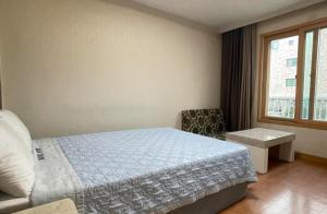 a bedroom with a bed and a chair and a window at Washington Motel in Gangneung