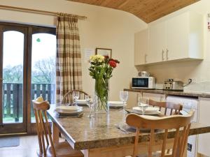 Una cocina y un comedor con una mesa con flores. en Woodside Lodge - Hw7520, en Penybont