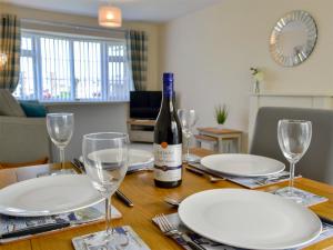 a bottle of wine sitting on a table with glasses at Gwynt Y Môr in Tywyn