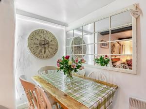a dining room with a table and a clock on the wall at Wellside Cottage in Starbotton