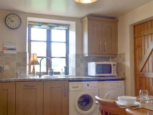 a kitchen with a washing machine and a microwave at Holly Bank in Crich
