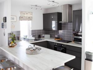 eine Küche mit schwarzen Schränken und einer weißen Arbeitsplatte in der Unterkunft Rose Cottage in Dingwall