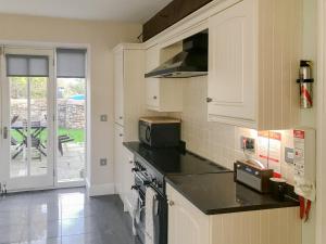 a kitchen with white cabinets and a stove top oven at Murton Cottage in East Ord