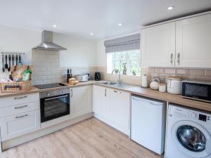 a kitchen with white cabinets and a washer and dryer at The Shambles in Fulletby