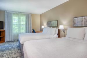 a hotel room with two beds and a television at TownePlace Suites Raleigh Cary/Weston Parkway in Cary