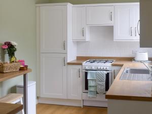 een keuken met witte kasten en een fornuis bij Tarn House in Wooler