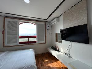 SongjŏngにあるGyeongpo Iris Stayのベッドと薄型テレビのある寝室