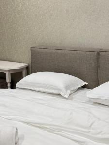a bed with white sheets and a pillow and a table at Hotel "CONTINENT" halal in Karagandy