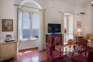 タオルミーナにあるホテル ベル ソッジョールノのテーブルと椅子と大きな窓のあるリビングルーム