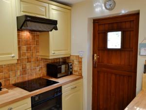 a kitchen with a stove top oven next to a door at Morlais - Hw7599 in Llanaber +4 photos