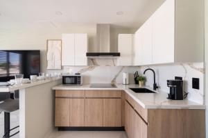 a kitchen with white cabinets and a black microwave at 2bedroom Lux house Isla Verde with Private Patio by PH in Carolina