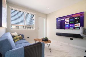 a living room with a blue couch and a flat screen tv at 2bedroom Lux house Isla Verde with Private Patio by PH in Carolina