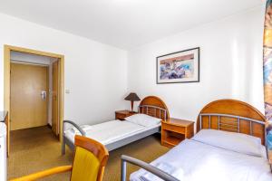 twee bedden in een kamer met twee tafels en stoelen bij Hotel CHOTOL in Horoměřice +21 foto's