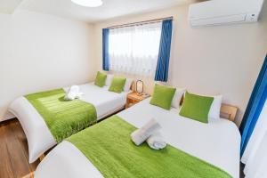 two beds in a room with green and white at 202 Room, a 6-minute walk from Tokyo Koiwa Station Direct connected to Shinjuku and Akihabara Stations Comfortable one-bedroom apartment with separate wet and dry areas in Tokyo