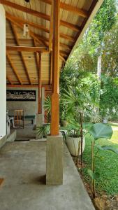 a patio with a wooden roof with plants and a table at Villa Bell Rose Hikkaduwa in Hikkaduwa