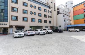 江陵市にあるGyeongpo Comodo Motelの建物前に停車する車両群