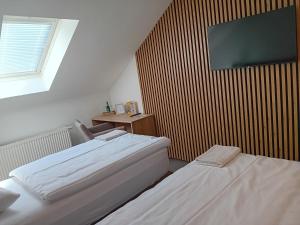 two beds in a room with a tv on the wall at Hotel u Budvaru in České Budějovice +42 photos