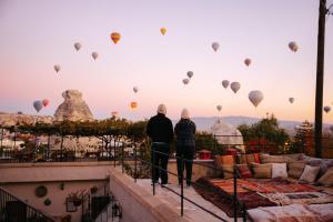 two people standing on a balcony looking at hot air balloons at Paradise Cappadocia Hotel & Rooftop in Göreme +89 photos