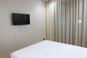 达布阿扎Dar Bouazza Luxury apartment with pools garden sports courts parking near the sea的一间房间,配有一张床和墙上的电视