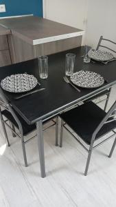 a black table with two plates and glasses on it at T2 refait à Neuf au calme avec TV et Fibre in Craponne