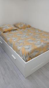 a bed with a white frame with a blanket on it at T2 refait à Neuf au calme avec TV et Fibre in Craponne