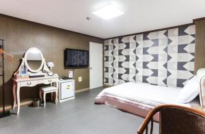 江陵市にあるGyeongpo Comodo Motelのベッドルーム(ベッド1台、洗面化粧台、鏡付)