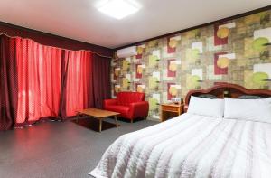 江陵市にあるGyeongpo Comodo Motelのベッドと赤い椅子があるホテルの部屋