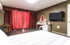 江陵市にあるGyeongpo Comodo Motelのベッドと薄型テレビがあるホテルの部屋 +9枚の写真