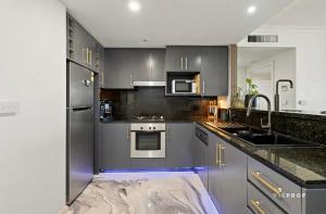una cucina con elettrodomestici in acciaio inossidabile e armadietti grigi di Penthouse Retreat in Heart ofCBD a Melbourne