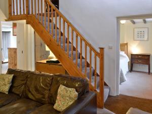 een woonkamer met een bank en een houten trap bij Dylasau Cottage in Capel Garmon
