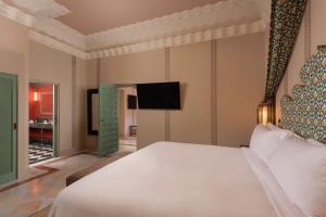 a bedroom with a white bed and a flat screen tv at Hotel Alfonso XIII, a Luxury Collection Hotel, Seville in Seville +160 photos