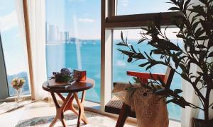a table and a plant in a room with a window at an emotional view of the sea at sunrise in Kwangan-dong