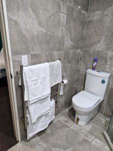La salle de bains est pourvue de toilettes blanches et de serviettes. dans l'établissement Master bedroom, à Tauranga