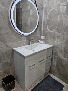 une salle de bains avec un lavabo blanc et un miroir dans l'établissement Master bedroom, à Tauranga 1 autre photo