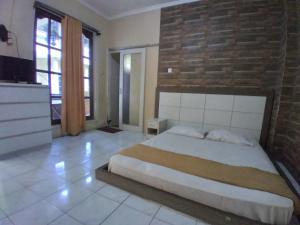 a bedroom with a large bed and a brick wall at Duta Kencana in Timuran