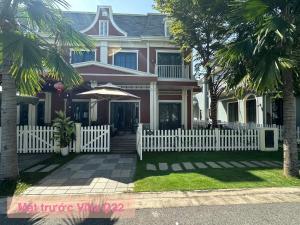 a pink house with a white picket fence and palm trees at Ho tram Beach Villa Biển Xuyên Mộc in Xuyên Mộc