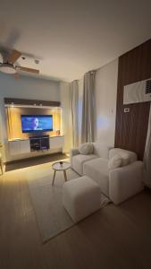 a living room with a white couch and a flat screen tv at Resort Condo in Trece Martires Cavite in Trece Martires