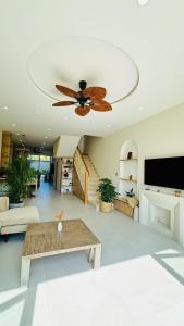 a living room with a ceiling fan and a table at LÚA de ROSY HOI AN in Hiếu Nhơn