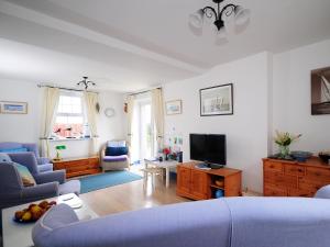 een woonkamer met een blauwe bank en een tv bij Bodarfor By The Sea in Aberdaron