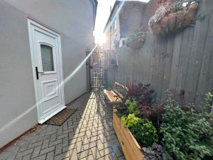 ブロムリーにあるCosy Studio Flatのフェンスの隣にドアとベンチがあるパティオ