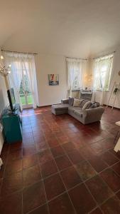 a living room with a tiled floor with couches and windows at il Casale di Adriana in Grugliasco