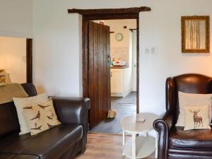 un salon avec un canapé en cuir et une table dans l'établissement The Bellringers Cottage, à Llandegla