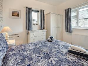 a bedroom with a bed with a blue and white bedspread at Stable Cottage - Uk10694 in Amroth