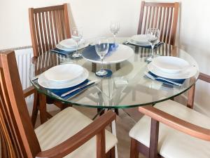 シャンクリンにあるLower Chine Apartmentのガラステーブル(椅子、皿、ワイングラス付)
