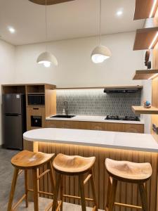 eine Küche mit Holzhockern und einer weißen Arbeitsplatte in der Unterkunft Amigo uluwatu in Uluwatu