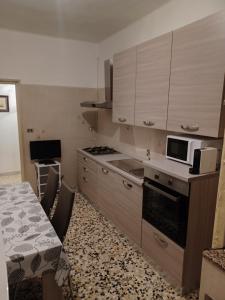 a kitchen with wooden cabinets and a table with a microwave at La bella Putignano in Putignano +13 photos